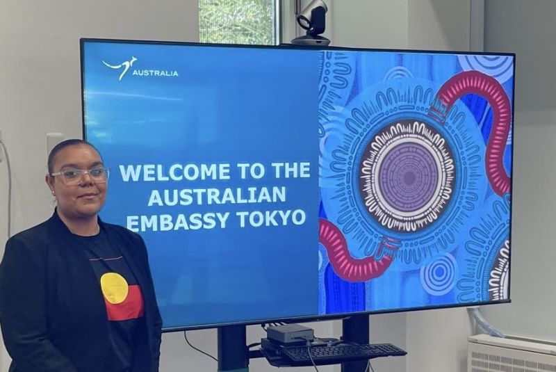 Photo of Helen Rose, founder of Helen Rose Pty Ltd, presenting at the Austrade tradeshow within the Australian embassy in Tokyo, standing in front of a screen showcasing her natural wellness brand.