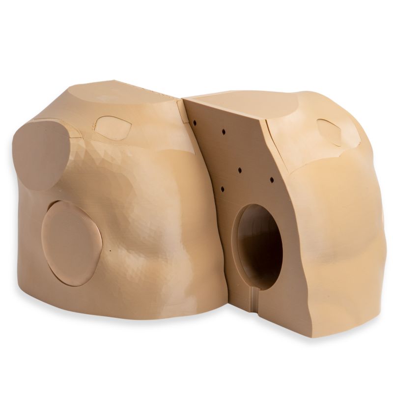 Photo of a close-up of a 3D-printed finger training model. 3D-printed plastic mold halves placed side by side, featuring smooth curved surfaces, circular cutouts, and small alignment holes, likely used for shaping or casting an object.