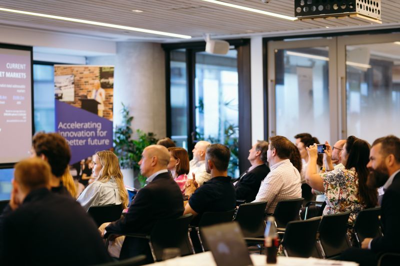 Audience members seated and attentively watching the Ignite+ graduation ceremony, celebrating the achievements of innovative Queensland businesses