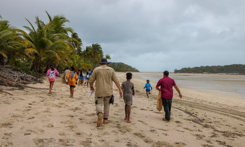 People walking along a beach collecting rubbish