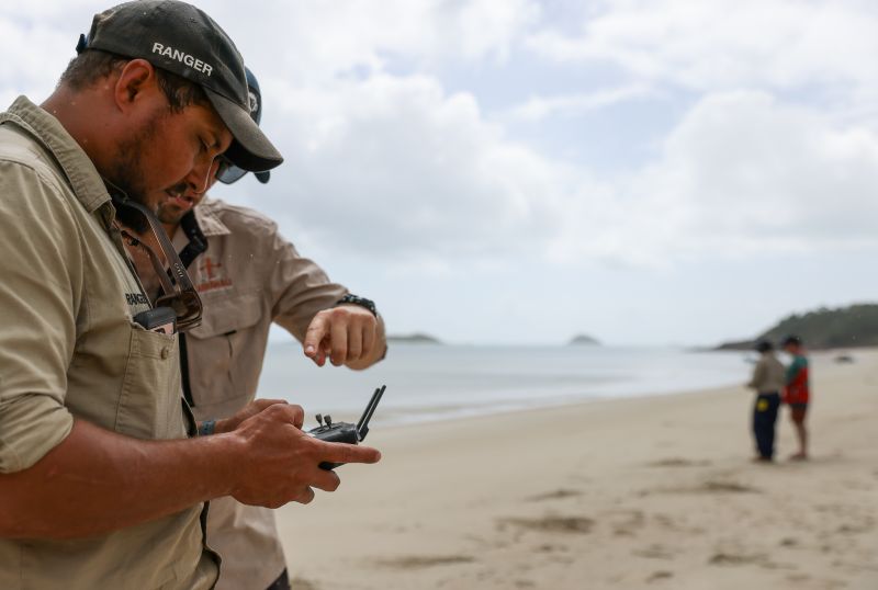 People on a beach operating a drone. 