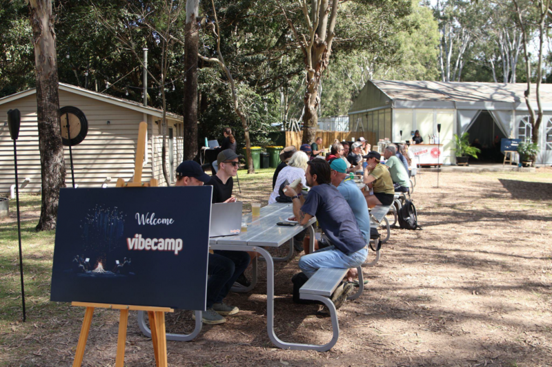 Photo of people talking while sitting outside at picnic tables