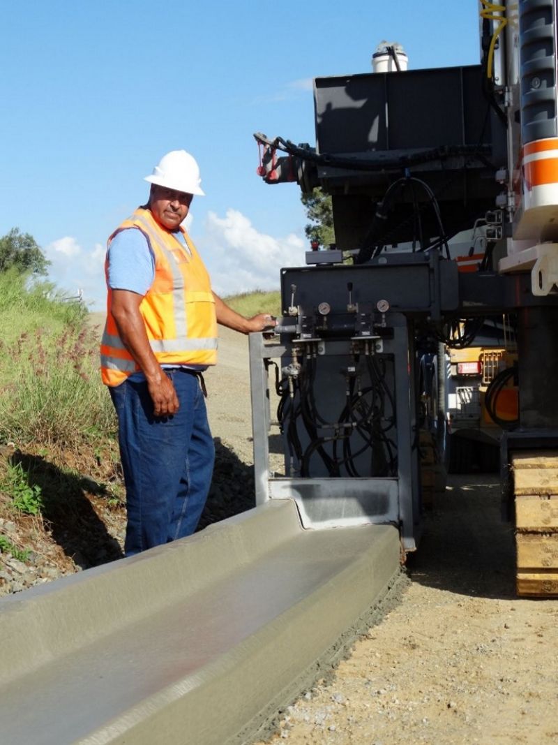 Person using GPS guided concreting machine to make concrete curb